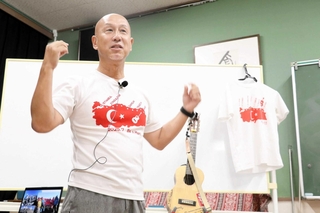 ギターを片手にトルコを横断した経験を語る藤本明生さん＝明石市魚住町金ケ崎