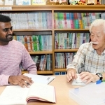 ボランティアの中村英夫さん（右）からレッスンを受けるシング・サントシュ・べニュゴパルさん＝明石市東仲ノ町