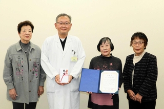 ケア帽子を寄贈した笑くぼ手作り帽子の会の中林妙子代表（左から３人目）と明石市民病院の久津見弘院長（同２人目）＝明石市鷹匠町