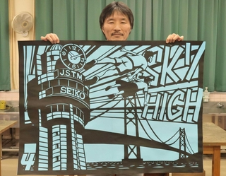 ４年生の課題曲をイメージした作品を持つ長谷川唯志教諭＝明石市魚住町清水