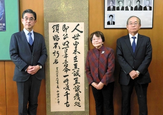 山内佐太郎がしたためた掛け軸を明石高校に寄贈した中本栄美子さん（中央）、原田良弘さん（右）と受け取った同校の泉村靖治校長＝明石市荷山町