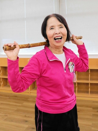 竹の棒を手に笑顔の新宅タケ子さん＝明石市東仲ノ町