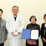 ケア帽子を寄贈した笑くぼ手作り帽子の会の中林妙子代表（左から３人目）と明石市民病院の久津見弘院長（同２人目）＝明石市鷹匠町