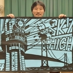 ４年生の課題曲をイメージした作品を持つ長谷川唯志教諭＝明石市魚住町清水