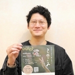 上映会のチラシを手にする田中大志監督＝明石市東仲ノ町