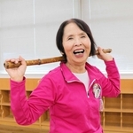 竹の棒を手に笑顔の新宅タケ子さん＝明石市東仲ノ町