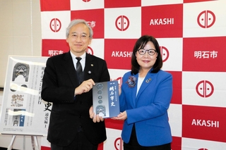 「新修明石市史通史編１」を手にする奥村弘委員長（左）と丸谷聡子市長。題字は丸谷市長の直筆＝明石市役所