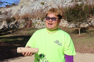 明石城の石垣をバックにモルック棒を持つ室屋拓さん＝県立明石公園