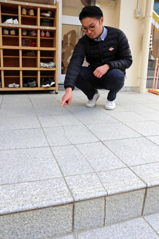 阪神・淡路大震災で入ったと伝わるひびを指さす石田求さん＝明石市東仲ノ町