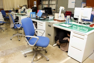 過去の訓練で机の下に潜る職員たち＝明石市役所