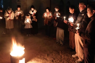 ろうそくを手に黙とうする人たち＝明石市東仲ノ町