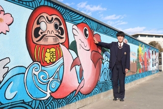 後輩たちと手がけた壁画を紹介する原田拓真さん＝明石南高校