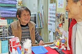 番台で客と談笑する岡本智恵子さん＝明石市大蔵天神町