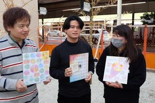 取引先や寄付者の言葉が記された色紙を手に、店舗建設の予定地に立つ（左から）森本晃司さんと絢斗さん、麻友美さん＝明石市本町１