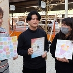 取引先や寄付者の言葉が記された色紙を手に、店舗建設の予定地に立つ（左から）森本晃司さんと絢斗さん、麻友美さん＝明石市本町１