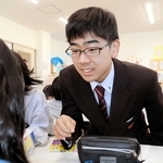 学習中の児童にアドバイスする明石高校の生徒＝人丸児童クラブ