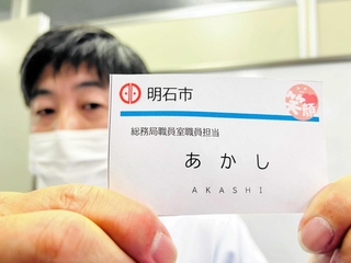 カスハラ対策の一環として明石市が導入した新たな職員の名札。顔写真と名字の漢字表記を削除している＝明石市役所