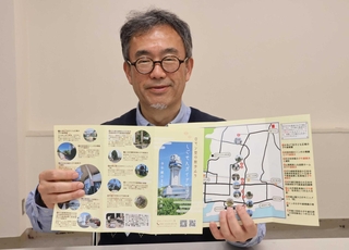 まち歩きのために作成したマップを持つ細谷真人さん＝明石市内
