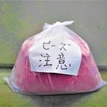 明石市が呼びかけるマイクロビーズ入りのクッションをごみ出しする方法。袋を二重にし、張り紙を付ける（同市提供）