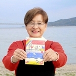 清掃活動を続ける望海浜で、２冊目の著書を手にする藤本真知子さん＝明石市船上町