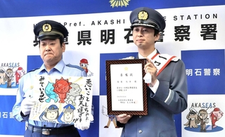 明石署で一日署長を務めた蓬莱大介さん（右）とイラストを受け取った足立雅樹署長＝明石署