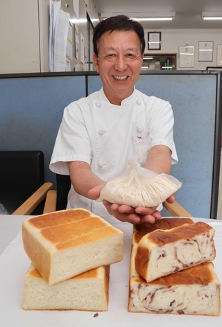酒かすを使った食パンを前に、酒かすパウダーを手にする中市雅章さん＝明石市硯町３