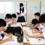 明石高校生の指導で自分の手を写生する子どもたち＝人丸小学校