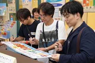 ジュンク堂書店明石店でのライツ社１０周年フェアの看板にメッセージを書く知念実希人さん（右）ら＝明石市大明石町１