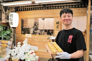 店前で明石焼きを持つ樟陽介さん＝明石市本町１