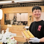 店前で明石焼きを持つ樟陽介さん＝明石市本町１