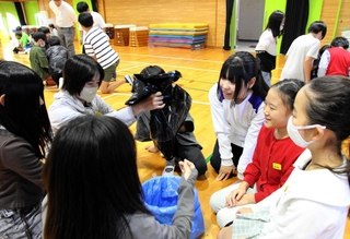 高校生から携帯トイレの使い方を学ぶ児童たち＝魚住小学校