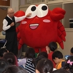 わさカーニの着ぐるみとともに児童らの質問に答える入江俊勝さん＝明石市和坂２