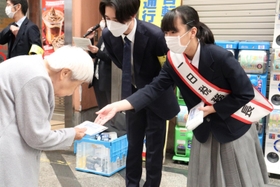 尼崎税務署の一日税務署長を務め、通行人に啓発用のマスクを手渡す川西凛子さん＝尼崎市昭和通３、中央商店街