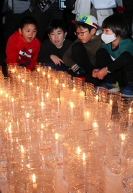 ６年ぶりの追悼式で、尼崎市内で亡くなった４９人を悼むろうそくを見つめる子どもたち＝尼崎市東七松町１