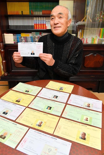 過去１２年の受験票を前に、目標達成を誓う土井章光さん＝淡路市