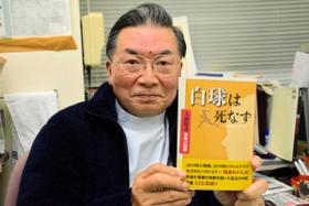 新たに出版された「白球は死なず」を手にする大鐘稔彦さん＝南あわじ市阿那賀