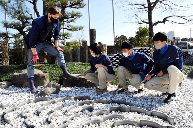 村雨辰剛さん（左）の庭園づくりに参加した県立農業高校の生徒＝南あわじ市八木養宜上、淡路ファームパーク・イングランドの丘
