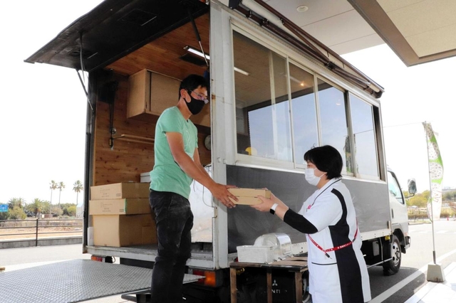 キッチンカーで作ったピザを手渡す石原さん（左）。医療従事者や病院利用者がひっきりなしに訪れた＝１７日、聖隷淡路病院
