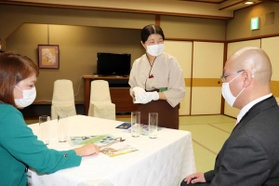 笑顔で接客する「おもてなしの心コンテスト」の参加者（中央）＝洲本市小路谷