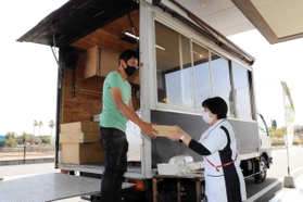 キッチンカーで作ったピザを手渡す石原さん（左）。医療従事者や病院利用者がひっきりなしに訪れた＝１７日、聖隷淡路病院