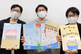 完成した絵本を持つ井川さん（中央）ら実行委のメンバー＝洲本市役所