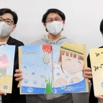 完成した絵本を持つ井川さん（中央）ら実行委のメンバー＝洲本市役所