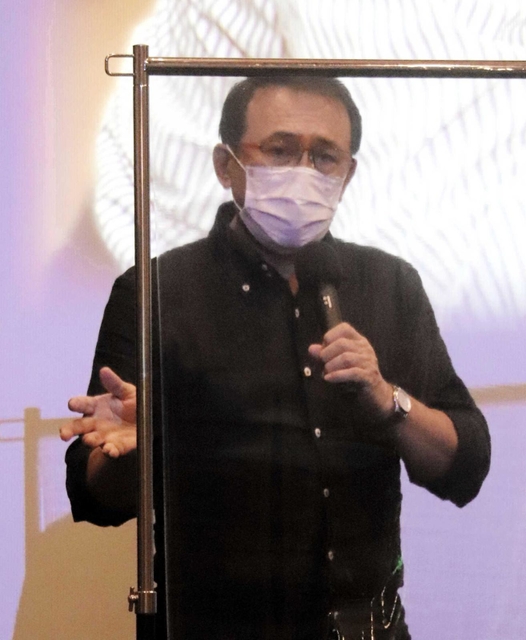 舞台あいさつで、コロナ感染防止の透明板越しに話す長尾和宏医師＝洲本オリオン