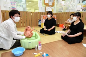 妊婦らに赤ちゃんのお風呂の入れ方を指導する浜田チヨ子さん（左）＝ファミリーサポートセンターまあるく