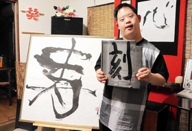 個展の会場で瓦に書いた作品を持つ岩元祐磨さん＝洲本市下加茂２