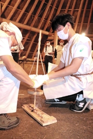 まいぎり式の道具で火おこしをする高田亮和さん（右）＝淡路市黒谷