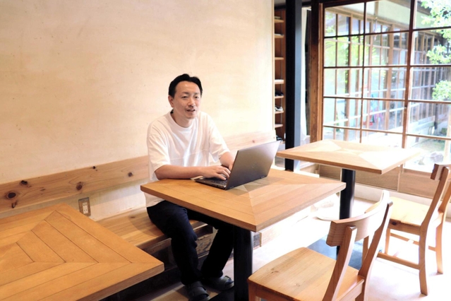 ５月に開設したワーケーション拠点で、パソコンを開く富田祐介社長＝洲本市本町７