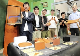 淡路島レザーのロゴを示す高原さん（左端）と、商品を持つ革作家ら＝淡路市塩田新島