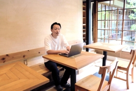 ５月に開設したワーケーション拠点で、パソコンを開く富田祐介社長＝洲本市本町７