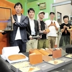 淡路島レザーのロゴを示す高原さん（左端）と、商品を持つ革作家ら＝淡路市塩田新島